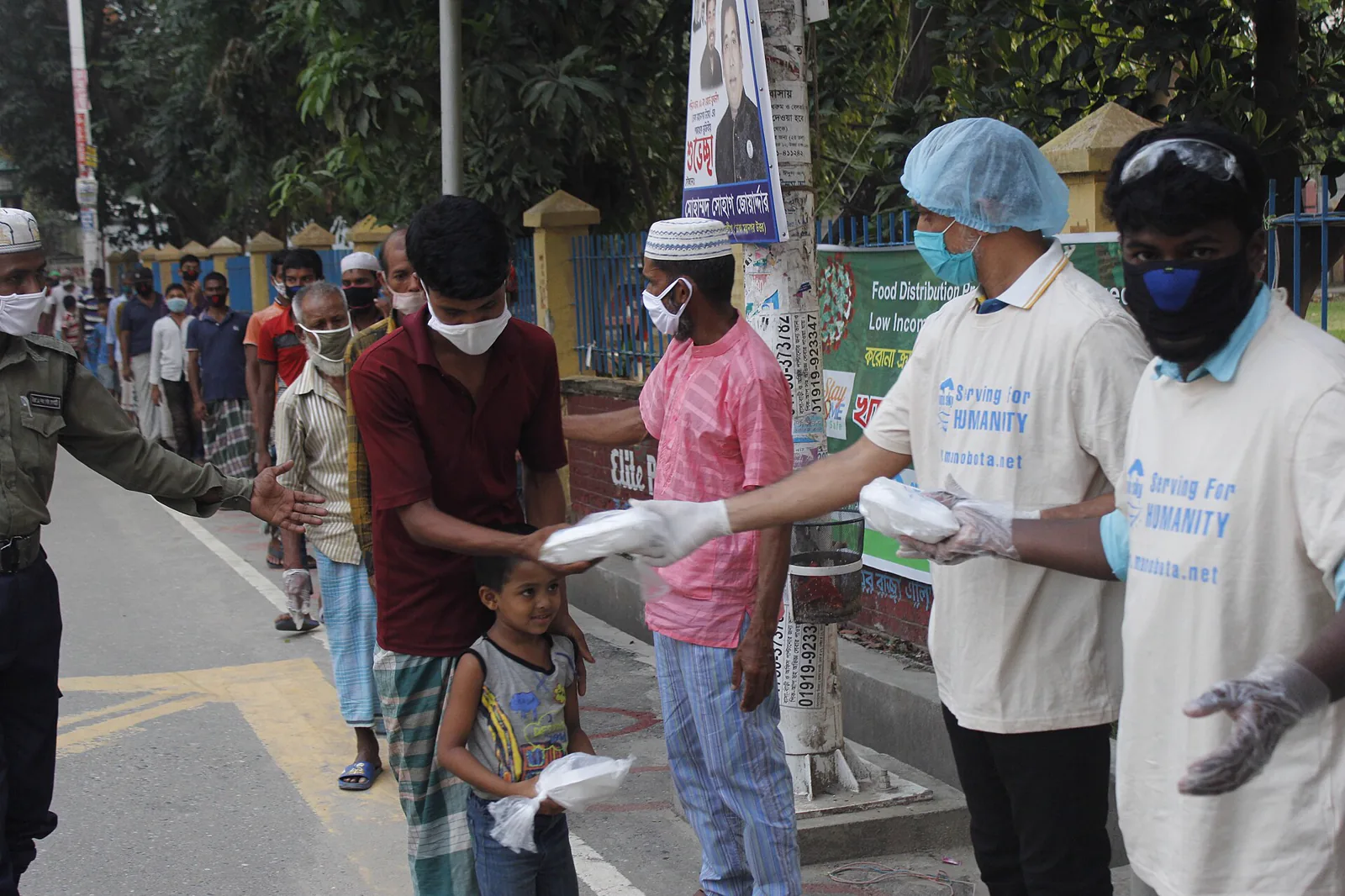 Volunteers handing out boxes of food at a community distribution site