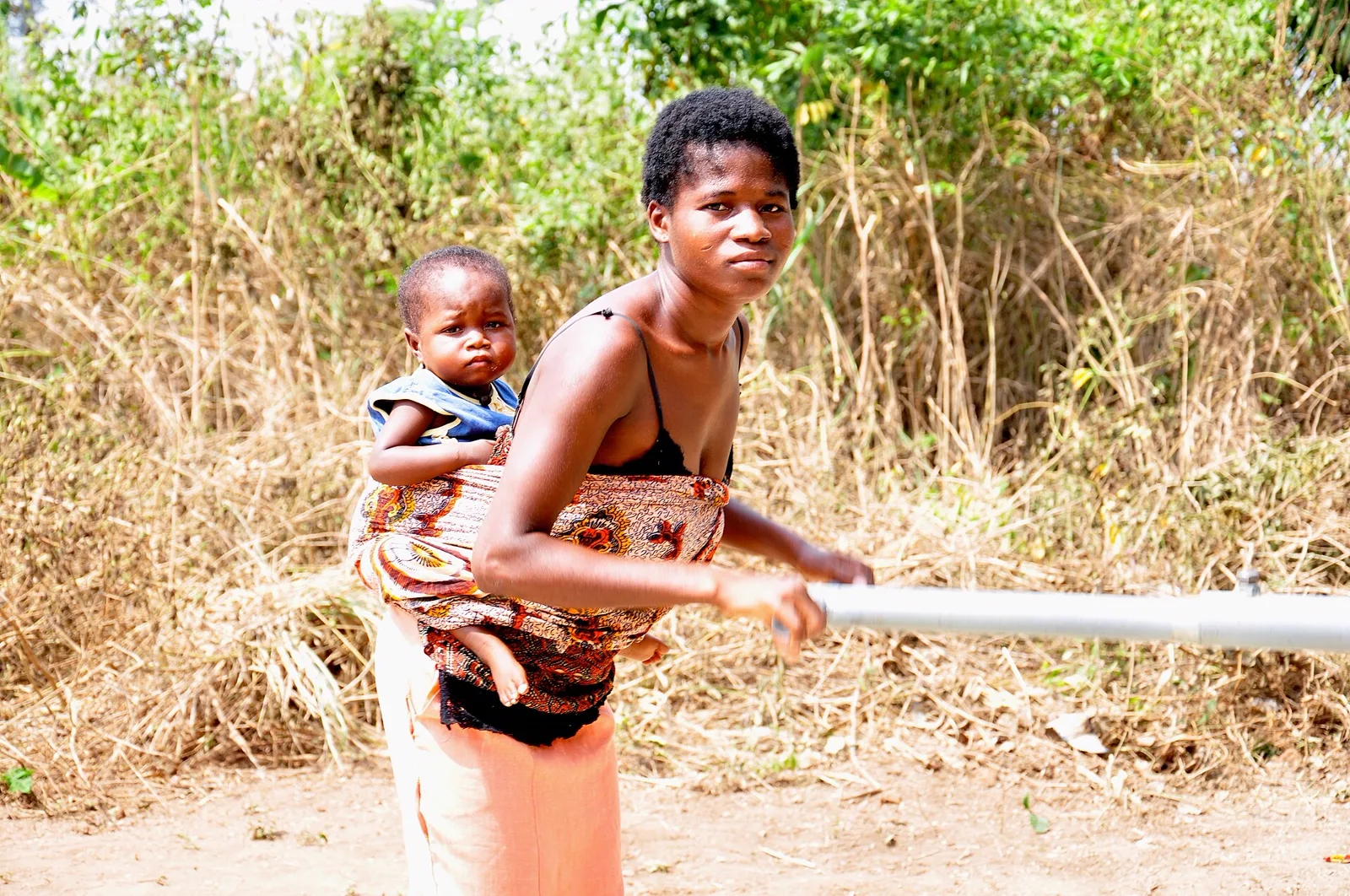 A mother and child collecting clean water at a village hand pump